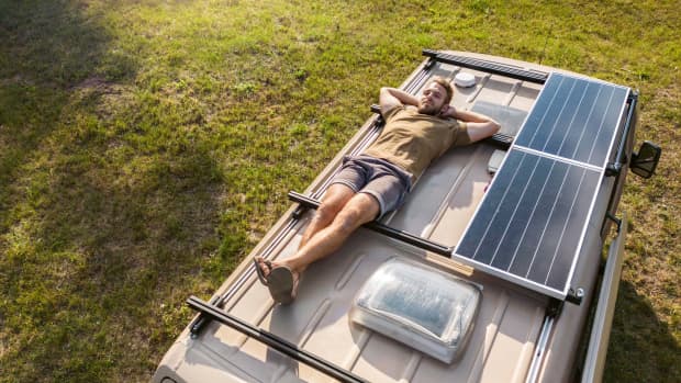 Mann liegt auf dem Rücken auf einem Wohnmobil. Spätsommerzeit mit Sonnenschein