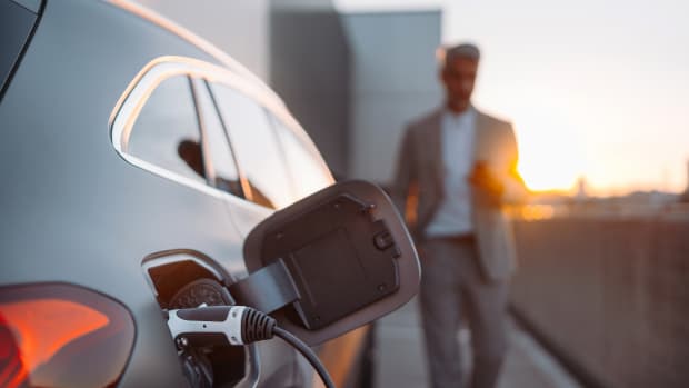 Ein Mann läuft auf sein Auto zu das gerade mit Strom geladen wird