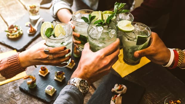 Fröhliche Freundesgruppe jubelt Mojito-Drinks in Cocktailbar