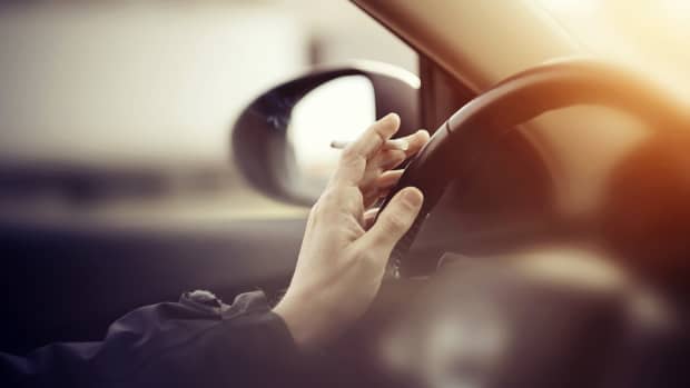 Mann mit Zigarette in der Hand fährt Auto
