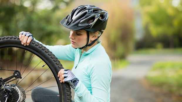 Eine Frau prüft den Fahrradreifendruck an ihrem Fahrrad