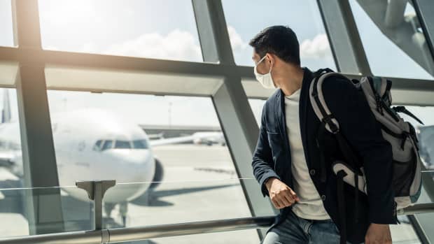 Eine Frau mit Corona Maske schaut auf Flugzeuge am Flughafen