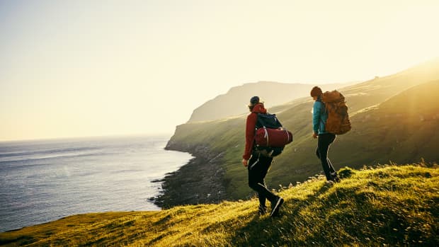 Ein Mann und eine Frau wandern mit Rucksack auf Klippen über dem Meer