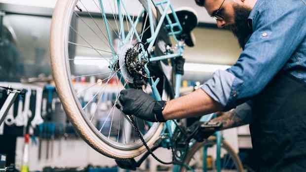 Der Schaltzug am Fahrrad wird von einem Mann repariert