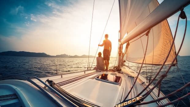Mann und Frau stehen am Bug eines Segelschiffs