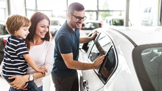 junge Familie begutachtet ein neues Auto beim Händler