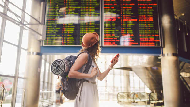 eine Frau steht vor einer Anzeigetafel am Flughafen