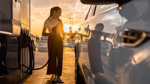 Eine Frau betankt ihr Auto an einer Tankstelle mit Benzin