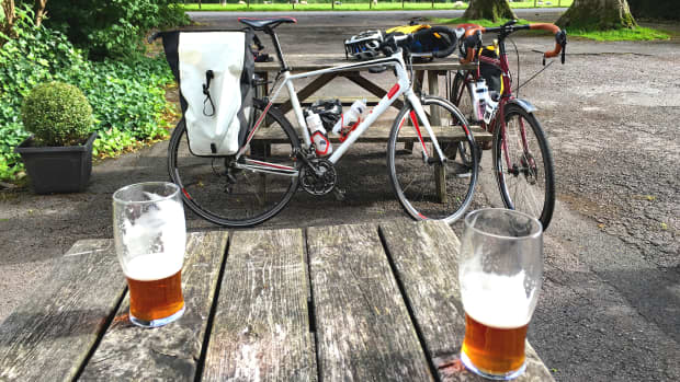 Zwei Biergläser stehen auf einem Tisch, im Hintergrund sind zwei Fahrräder zu sehen
