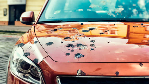 Rotes Auto mit viel Vogelkot auf der Motorhaube