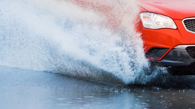 Auto fährt über eine überschwemmte Strasse