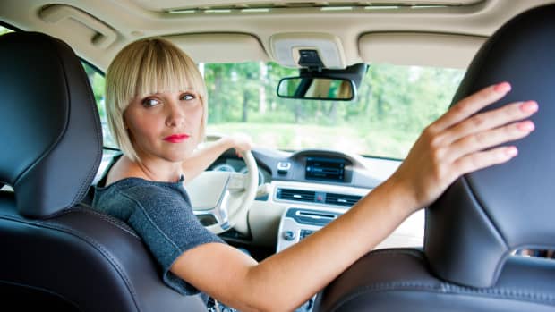 Eine Frau blickt beim Rückwärtsfahren über ihre Schulter nach hinten