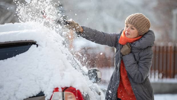 Frau kratzt Schnee und Eis von ihrem Auto