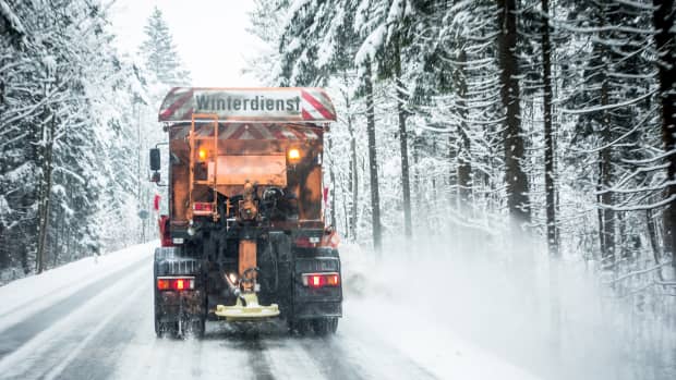 Ein Winterdienst Auto fährt auf einer verschneiten Straße