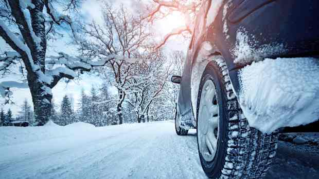 Nahaufnahme von einem Winterreifen auf einer schneebedeckten Straße