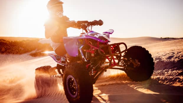 Ein Quadfahrer fährt über eine Sanddüne