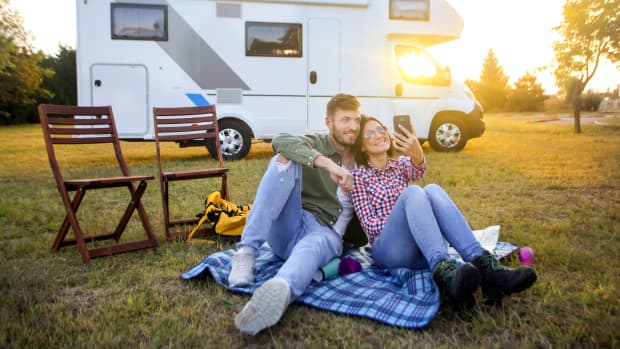 Pärchen sitzt vor einem Wohnmobil und macht ein Selfie