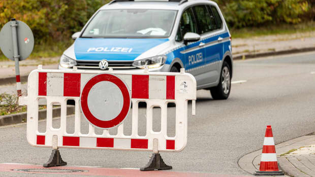 Ein Einsatzfahrzeug der Polizei mit Blaulicht und Schriftzug hinter einer Absperrung