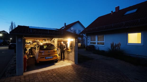Ein älterer Mann der in der Nacht sein E-Auto Zuhause lädt
