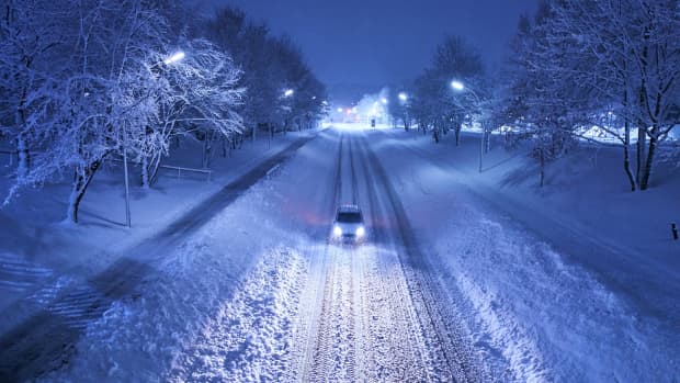 ein Auto fährt Nachts auf verschneiter Strasse