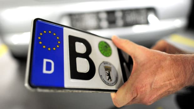 Ein Mann hält ein Autokennzeichen in der Hand