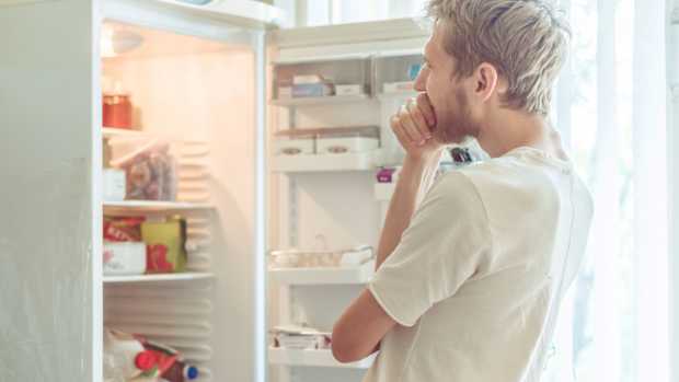 Ein Mann steht vor einem offenen Kühlschrank