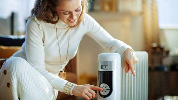 Eine frau bedient einen Ölradiator als Zusatzheizung in ihrem Wohnzimmer