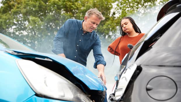 Eine Frau und ein Mann betrachten den Schaden nach einem Verkehrsunfall