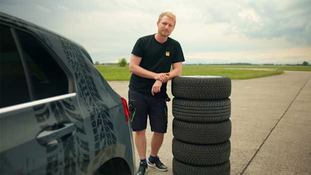 ADAC Ingenieur Christoph Pauly lehnt auf einem Stapel mit Winterreifen