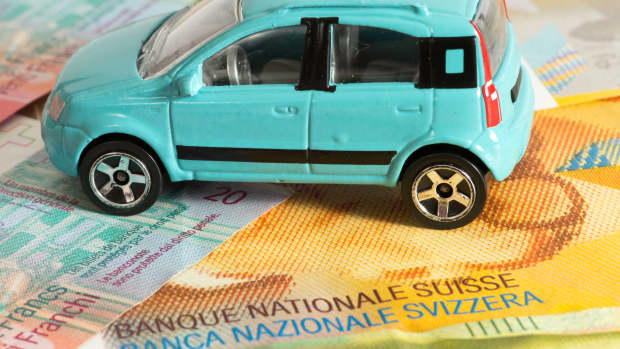 Schweizer Banknoten und ein Spielzeugauto liegen auf dem Tsich