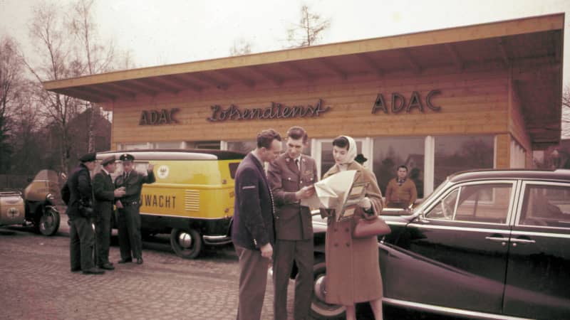 Eine Strassenwachtsstation mit Autos und Menschen davor in den 50er Jahren