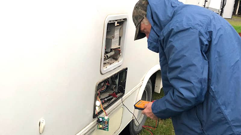 Mann versucht die Heizungselektrik an seinem Wohnmobil zu reparieren