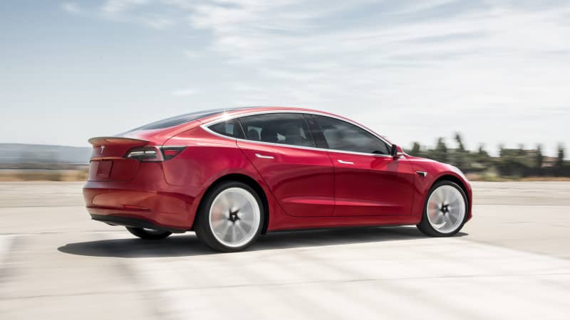 rotes Tesla Model 3 Seitenansicht fahrend