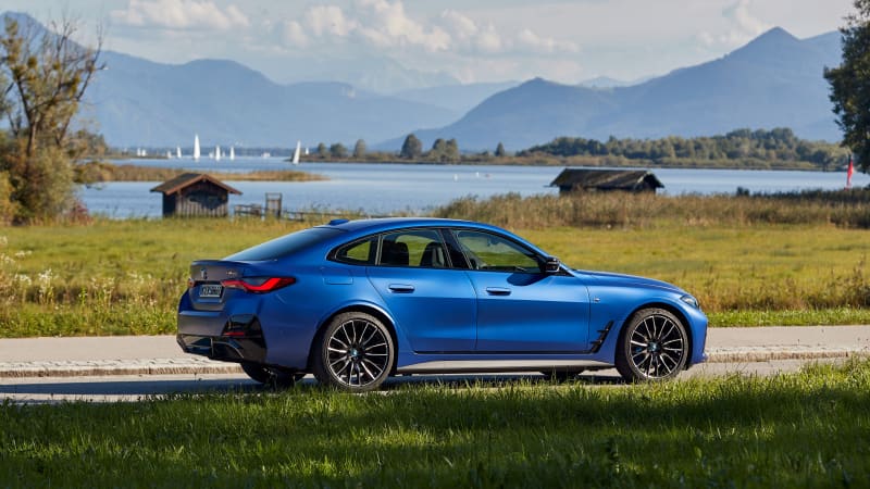 Der neue blaue BMW i40 parkend von der Seite vor einem See mit Bergkulisse