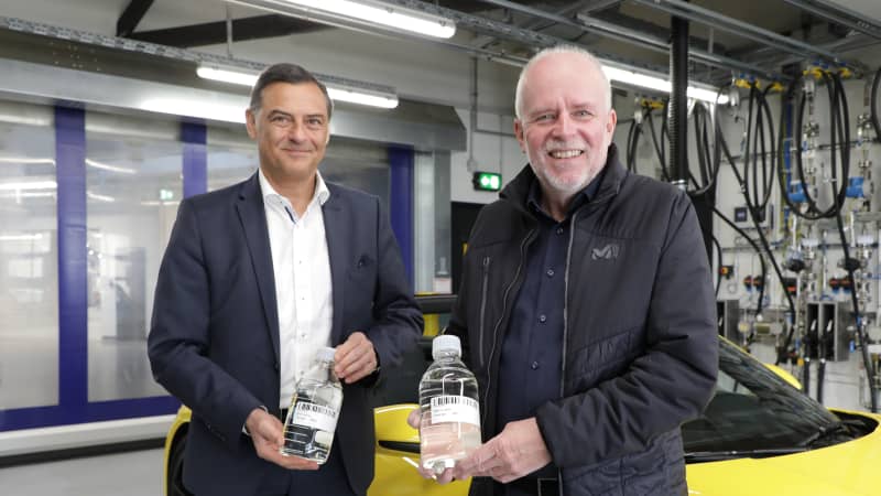 Porsche Entwicklungs- Vorstand Dr. Michael Steiner und ADAC Redakteur Wolfgang Rudschies halten Flaschen mit synthetischen Kraftstoff in den Händen