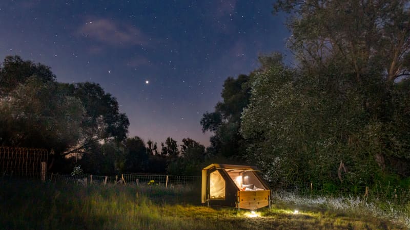 Ein Bett aus Holz gebaut steht unter freiem Sternenhimmel