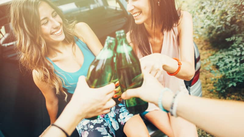 Frauen trinken Alkohol im Kofferraum eines Autos