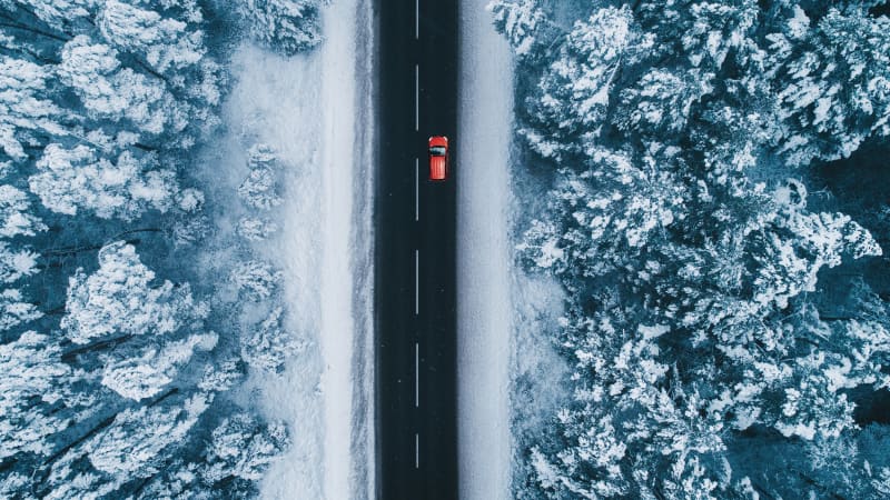 Rotes Auto fährt auf einer Strasse in einer verschneiten Landschaft, betrachten aus der Vogelperspektive