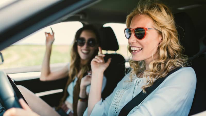 Zwei junge Frauen hören im Auto Musik