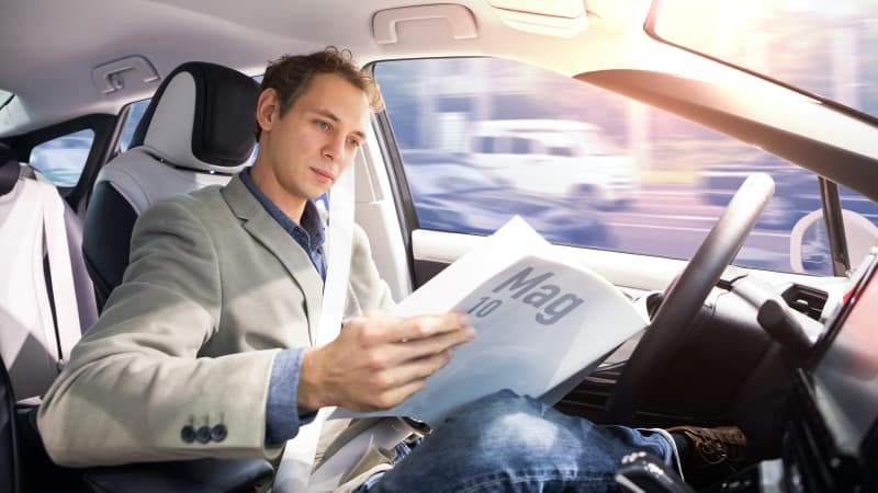 Mann liest Zeitung im autonomen Fahren