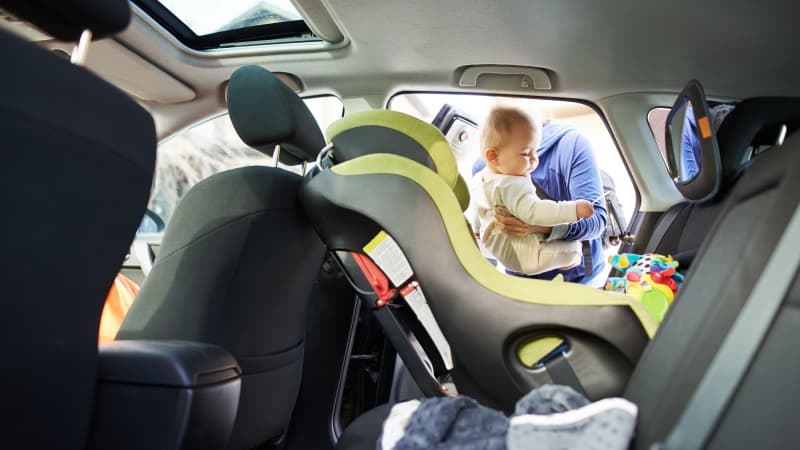 Baby wird von Frau in einen Kindersitz im Auto gesetzt