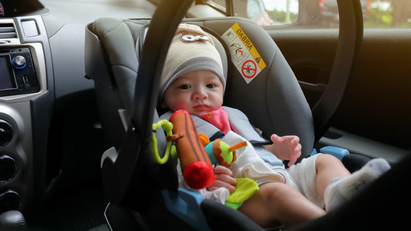 Baby sitzt im Kindersitz auf dem Beifahrersitz im Auto