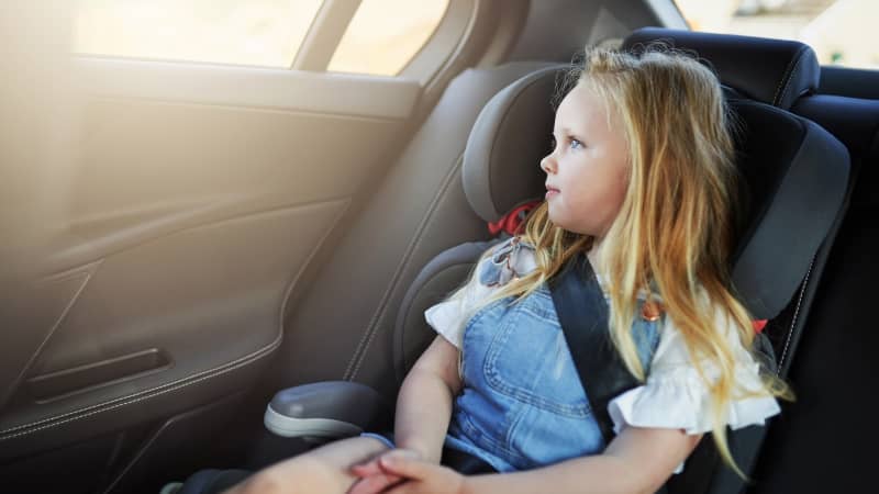 Mädchen sitzt angeschnallt im Kindersitz im Auto