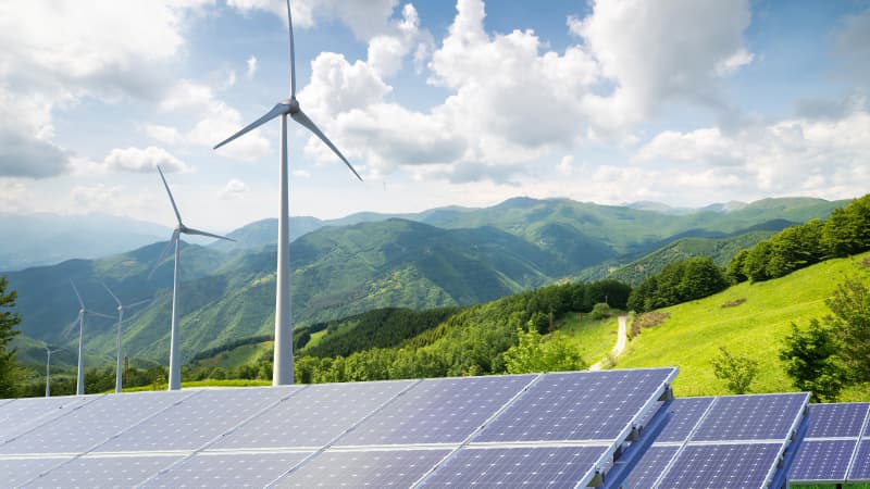 Solarzellenpark und Windräder vor grüner Landschaft