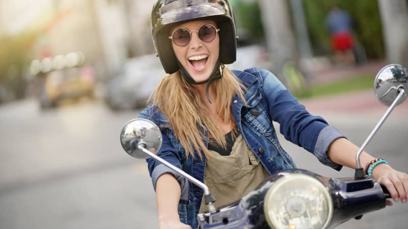 Junge Frau fährt auf einem Moped
