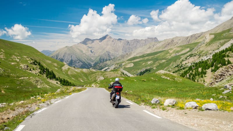 Ein Motorrad fährt auf einer Strasse durch einen Gebirgslandschaft