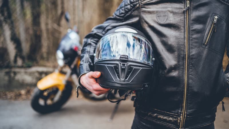 Ein Motorradfahrer hält seinen Helm unter dem Arm