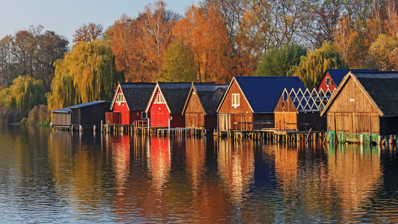 Bootshäuser an einem See im Herbst