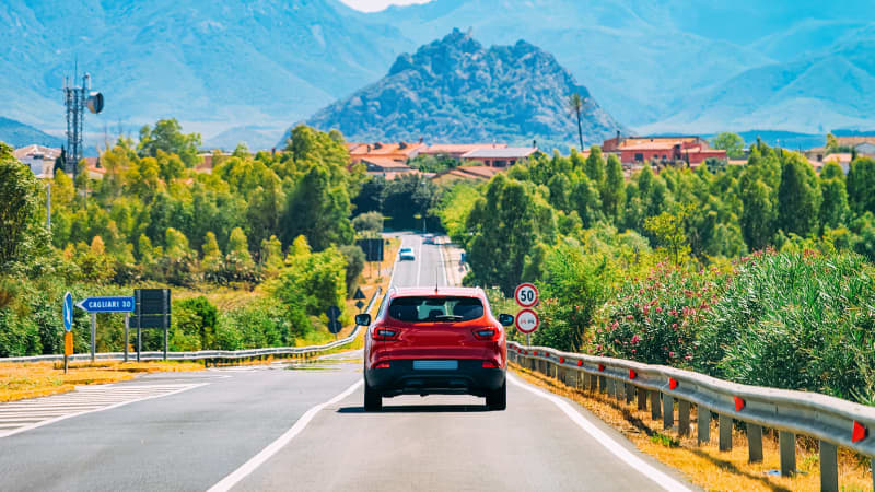 Rotes Auto fährt durch italienische Landschaft