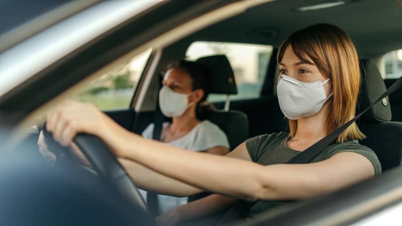 Zwei Frauen fahren mit Mund-Nasen-Schutz Auto